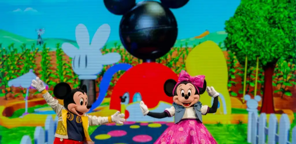 Mickey and Minnie Mouse waving on the colorful Mickey Mouse Clubhouse stage set