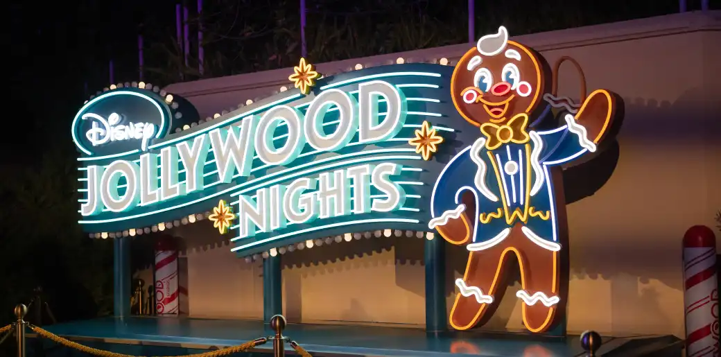 Neon sign featuring Disney Jollywood Nights with a smiling gingerbread figure waving and dressed in festive clothing.