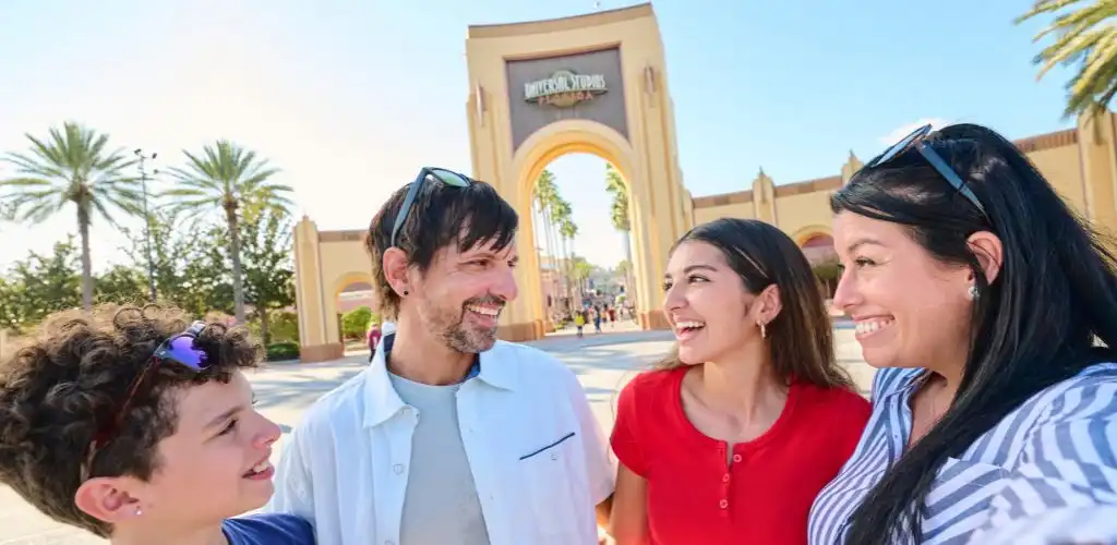 Happy family standing in front of the Universal Studios Florida entrance, sharing smiles before an exciting day at Universal Orlando Resort.