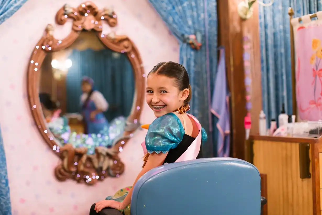 Smiling young girl transformed into a princess at Bibbidi Bobbidi Boutique in Magic Kingdom Park, wearing a royal sash and a sparkling dress