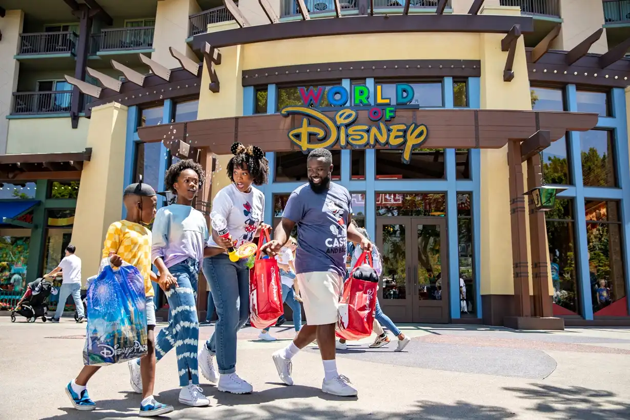 Happy family shopping at World of Disney in Disney Springs, carrying bags filled with magical merchandise from the largest Disney store