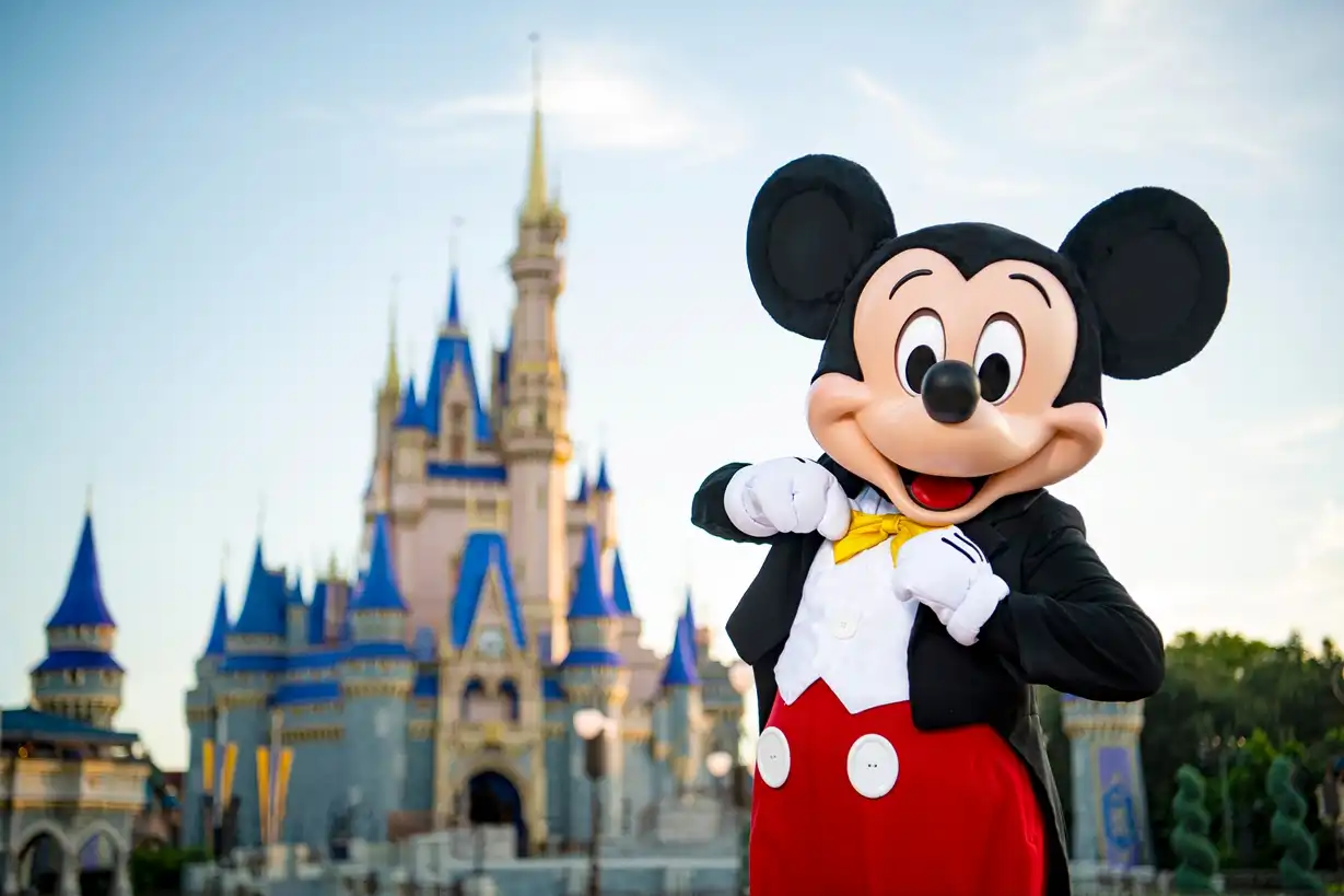 Mickey Mouse posing in front of Cinderella Castle at Magic Kingdom Park, welcoming guests with his signature charm and classic tuxedo