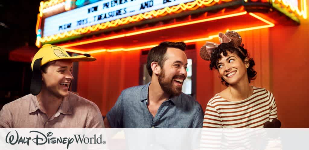 Three friends laughing and enjoying their time at Disney’s Hollywood Studios After Hours, with glowing neon lights in the background creating a vibrant night setting