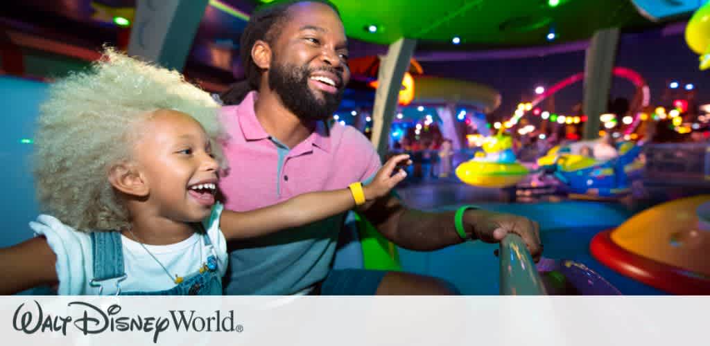 A father and daughter laughing together while enjoying a thrilling ride at Disney’s Hollywood Studios After Hours, surrounded by colorful nighttime attractions