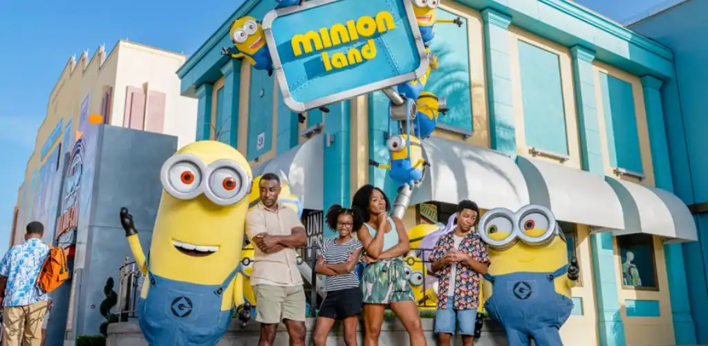 Guests posing with playful Minions at Minion Land in Universal Studios Florida, surrounded by vibrant buildings and whimsical decorations.