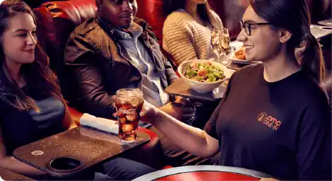 A group of people enjoying a meal together at a restaurant, with a table filled with various dishes and drinks.