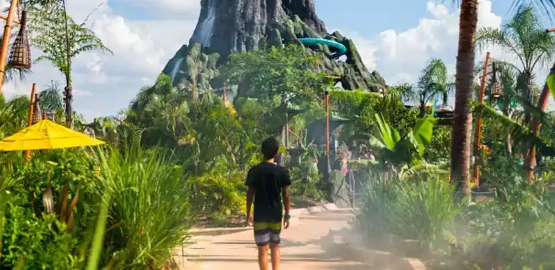 Guest walking towards the towering Krakatau volcano at Universal’s Volcano Bay, surrounded by lush tropical scenery and thrilling water slides.