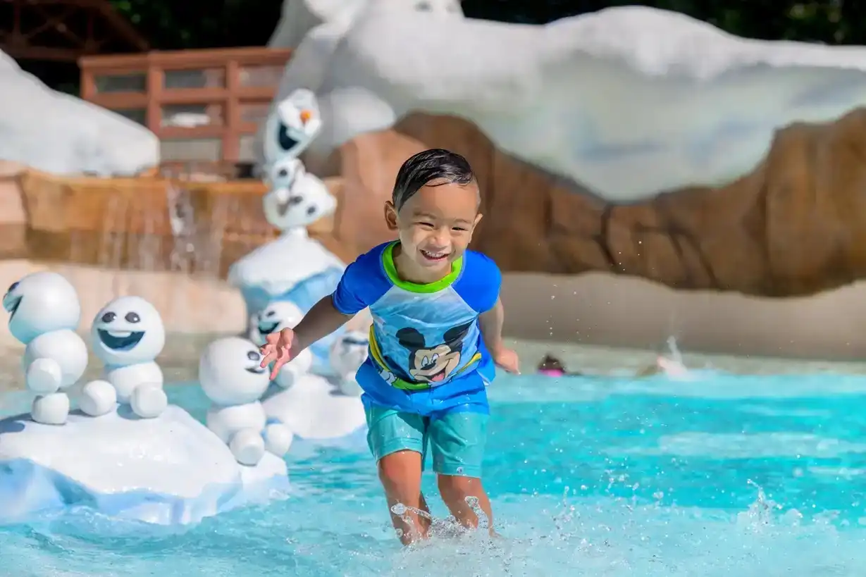 Young child splashing through the water at Disney’s Blizzard Beach, surrounded by Frozen-themed Snowgies
