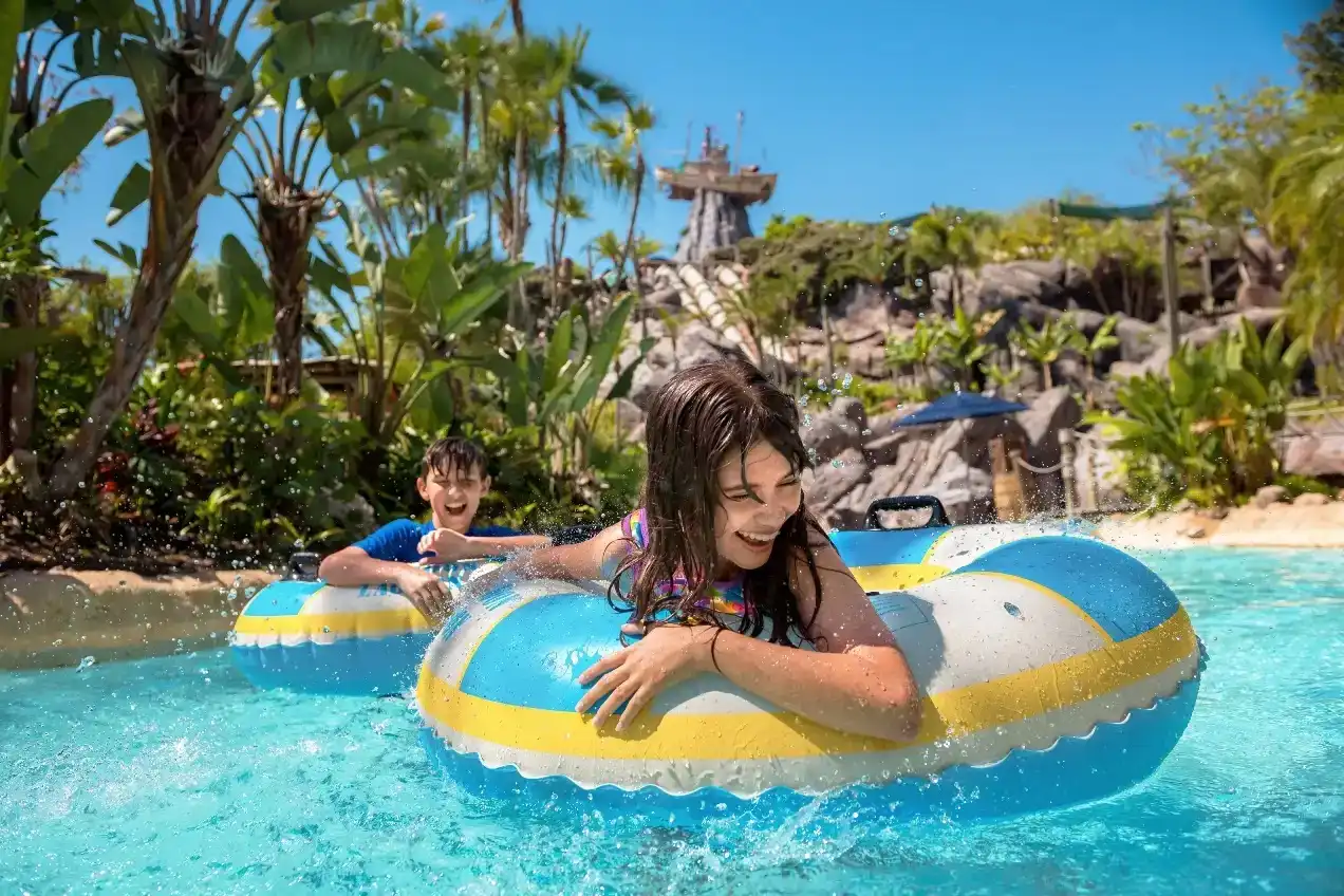 Kids floating on inner tubes in the lazy river at Disney’s Typhoon Lagoon, surrounded by tropical scenery and a bright blue sky