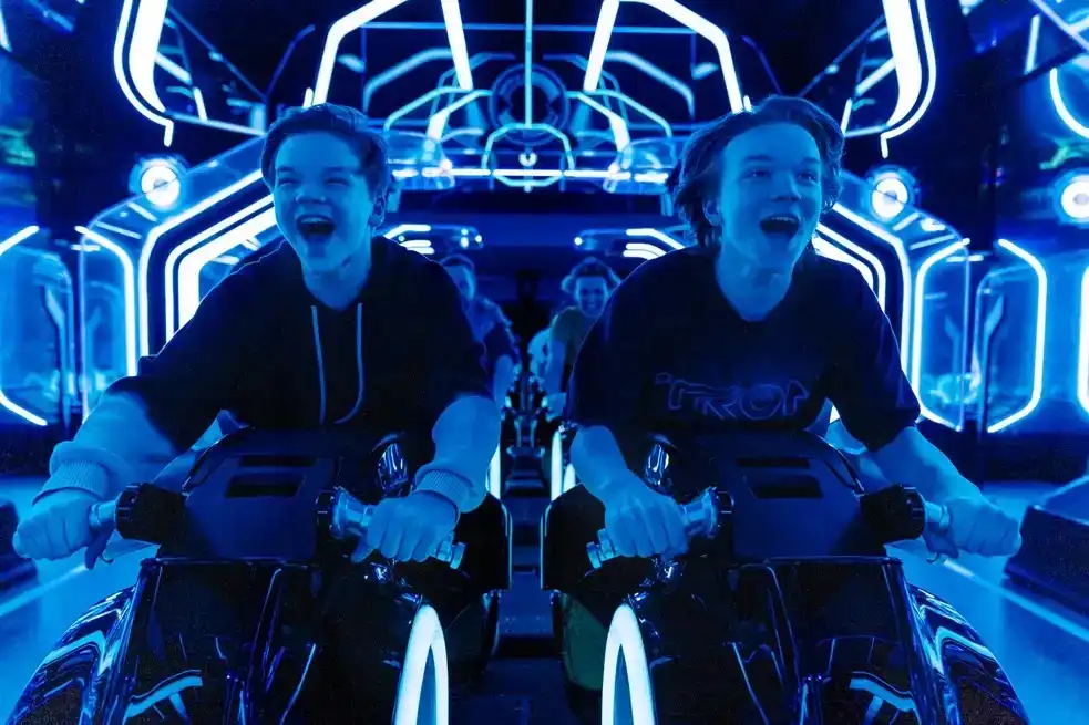 Thrill-seekers racing through the neon-lit digital world of TRON Lightcycle / Run at Magic Kingdom Park, immersed in the high-speed adventure. 