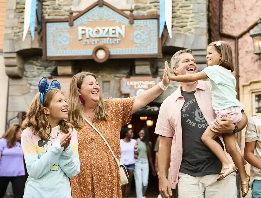 Happy family sharing a magical moment outside Frozen Ever After at EPCOT, as they celebrate the enchanting world of Arendelle
