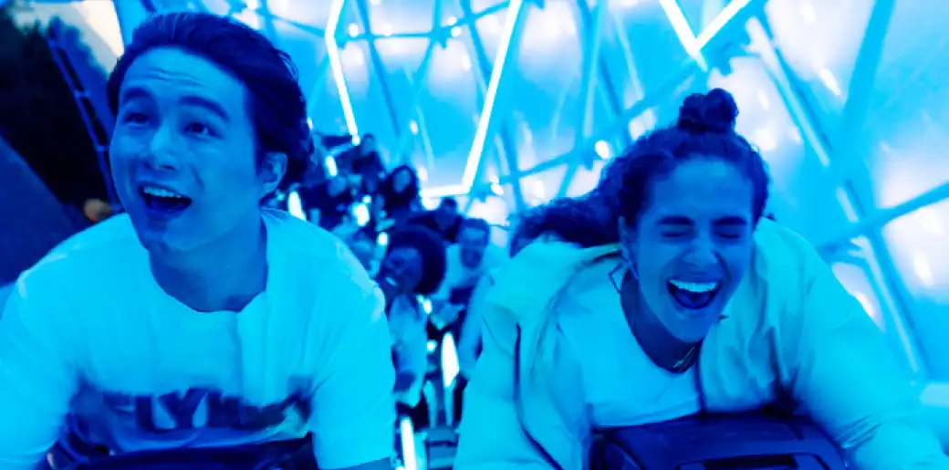 People smiling and enjoying a thrilling ride inside a colorful illuminated structure at funex.com
