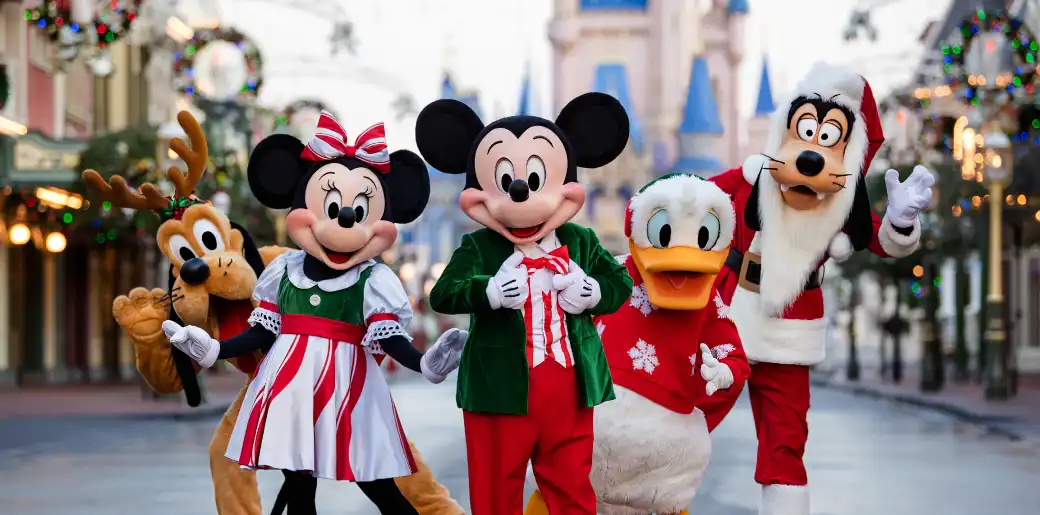 Disney characters including Mickey Mouse Minnie Mouse Donald Duck Daisy Duck and Goofy dressed in Christmas outfits standing together in a festive park setting