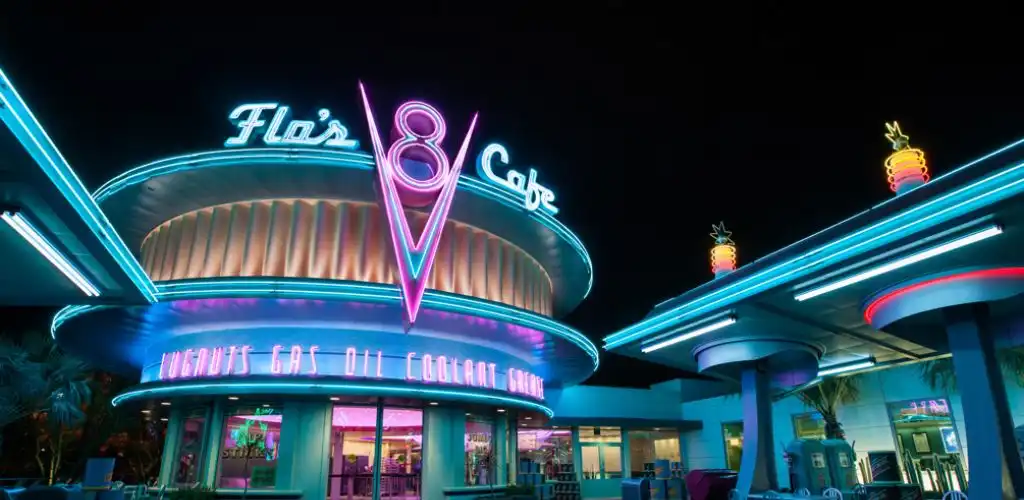Neon-lit sign for Flas V Cafe with colorful lighting and retro design elements at night.
