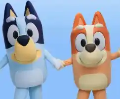 Two cartoon dogs, one blue and one orange, holding hands and smiling against a clear blue sky.