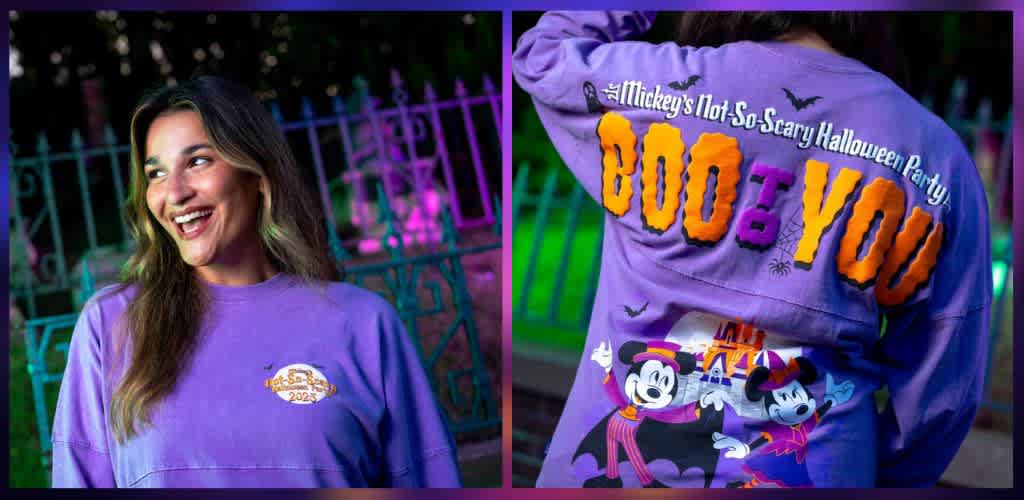 A young woman wears a purple Halloween-themed shirt with Mickey Mouse and playful text, smiling happily in a festive outdoor setting at night.