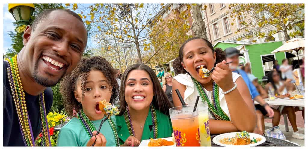 Family celebrating at an outdoor event with food, drinks, and colorful beads in the fall, smiling and enjoying a festive atmosphere.