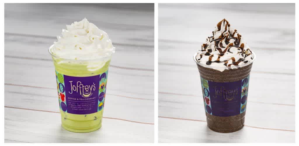 Two whipped cream-topped iced drinks in colorful cups from Joffreys on a white surface.