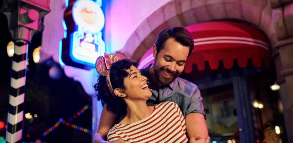 A smiling couple enjoying a night out at funexcomanco with colorful neon lights and a lively atmosphere