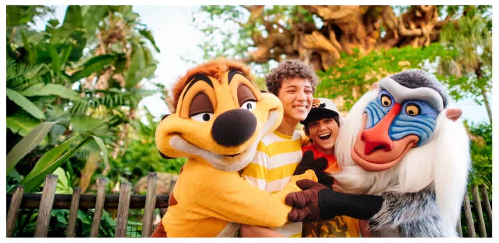 Three children with two characters from Disney's The Lion Guard smiling and hugging outdoors among lush greenery.