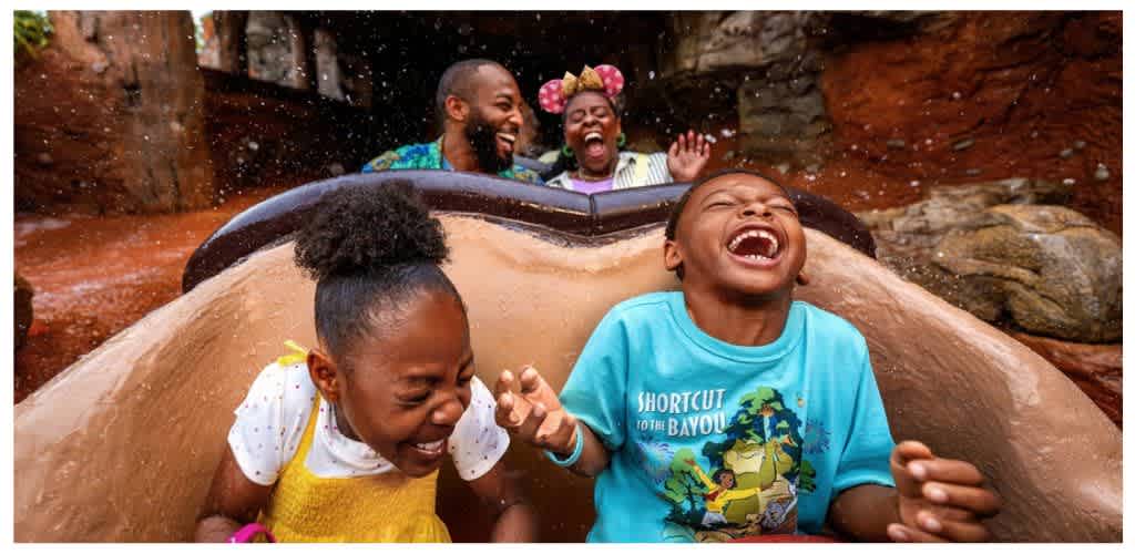 Four children laughing and enjoying a water ride on a log flume at an amusement park