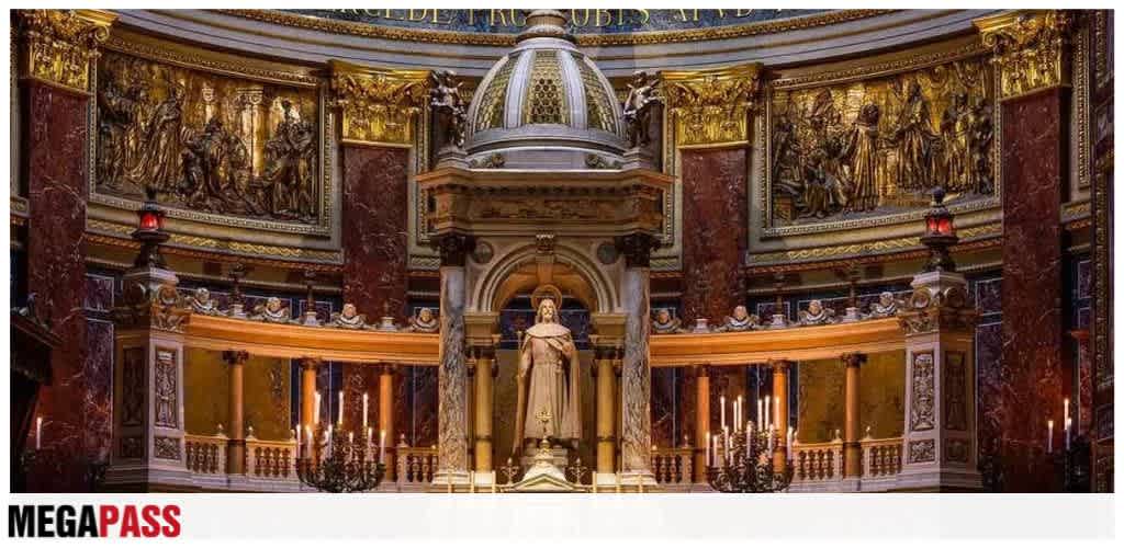 Interior view of a grand church featuring ornate gold and marble decorations, chandeliers, and a prominent statue at the center