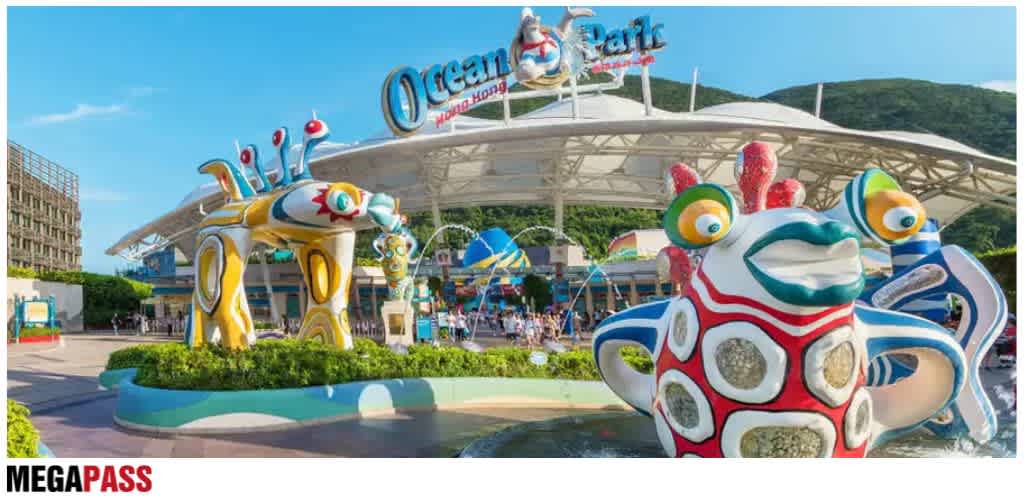 Colorful sea creature sculptures at an outdoor water park with a large canopy and mountain background
