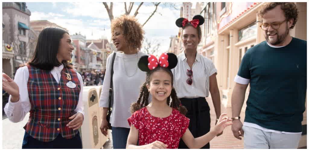 A group of diverse people walking together in a theme park, smiling and enjoying the day with amusement park attractions in the background.