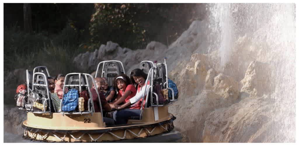 Group of children enjoying a water ride in a circular raft with water spray in the background