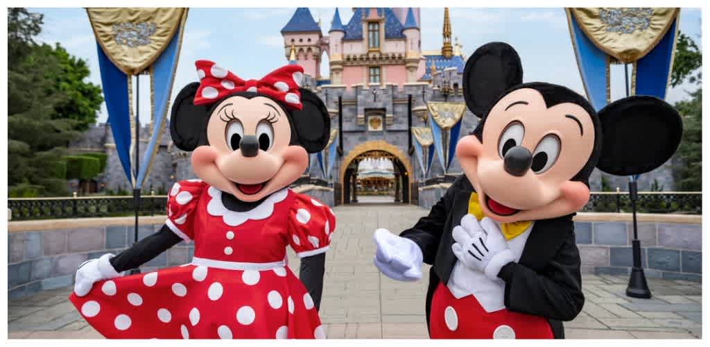Mickey and Minnie Mouse characters in costume at Disneyland with a castle background during daytime