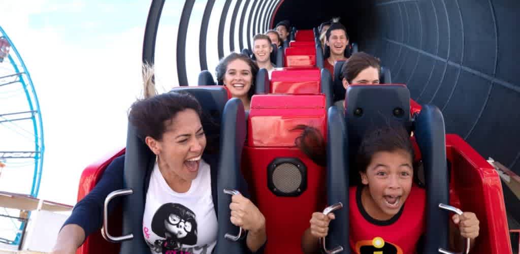 A group of people enjoying a roller coaster ride on a colorful amusement park coaster with smiling faces and excitement.