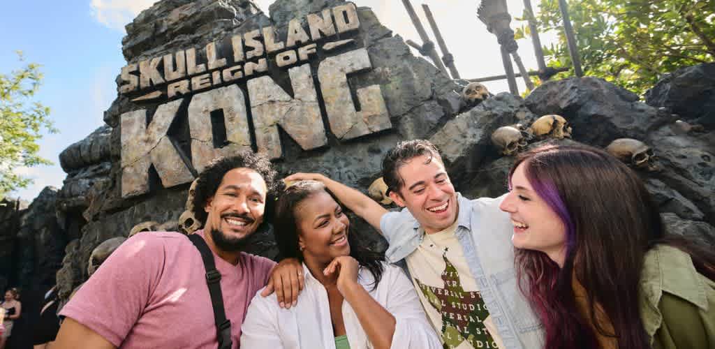 Group of diverse friends smiling and enjoying themselves in front of Skull Island Reign of Kong attraction at an amusement park