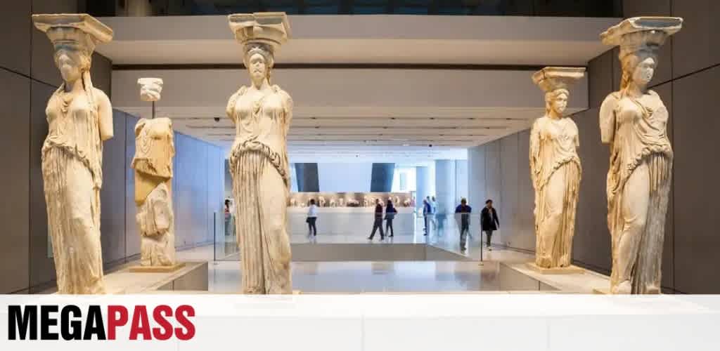 Ancient Greek marble statues displayed in a modern museum corridor with visitors in the background.