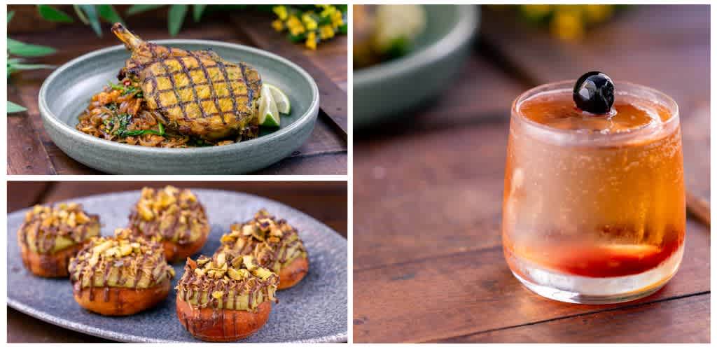 A grilled meat dish on rice, four decorated cupcakes, and a cocktail with ice and a cherry on top sitting on a wooden surface