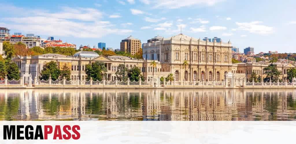 A historic building with classical architecture reflected in calm water with a cityscape in the background under a partly cloudy sky