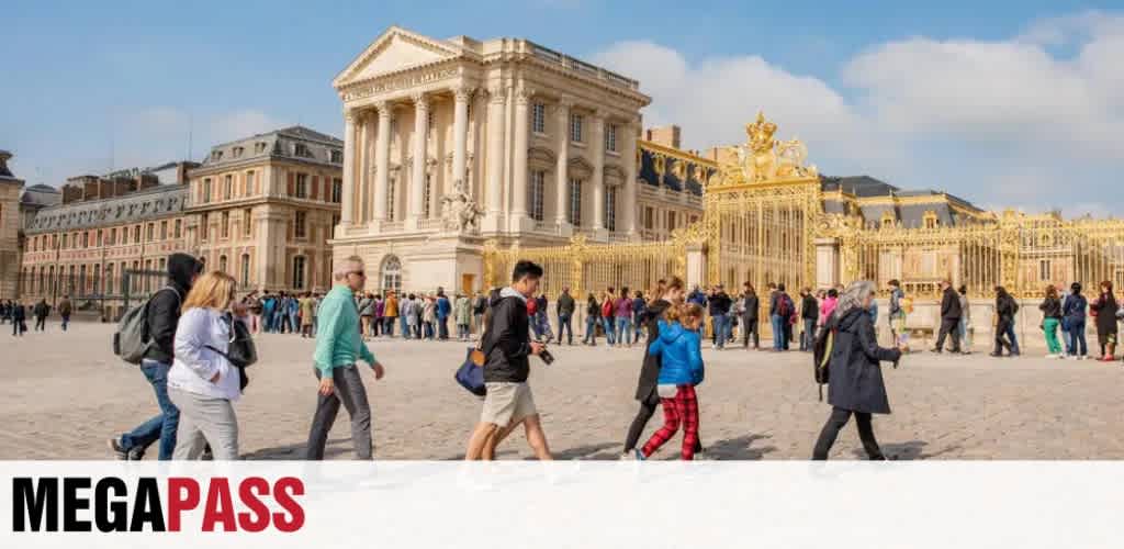 People walking on a historic European square with a grand building and ornate golden gate in the background