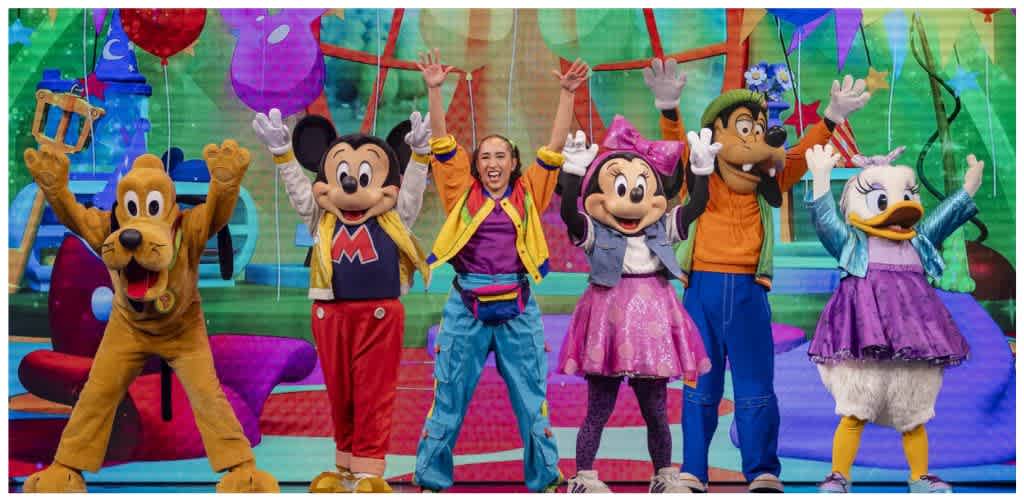 Costumed characters including Mickey Mouse, Minnie Mouse, Pluto, Goofy, and Daisy Duck celebrating on a colorful stage.