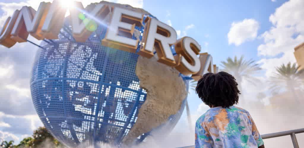 A person with curly hair wearing a colorful shirt looks at a large globe with the word Las Vegas above it