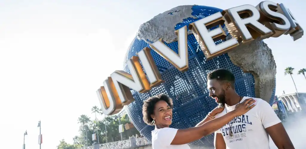 A couple smiling and embracing in front of a globe-shaped Universal Studios sign at the theme park