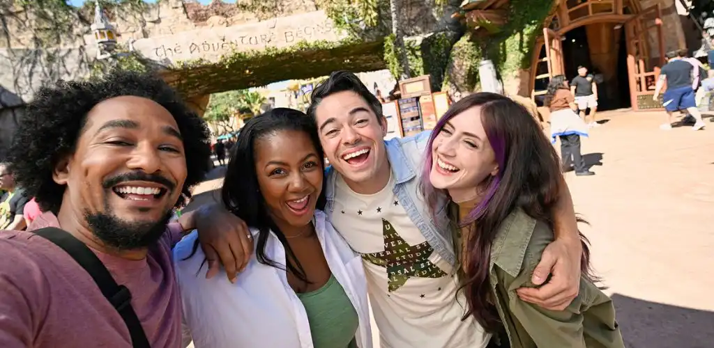 Group of diverse friends smiling and embracing in an amusement park outdoors on a sunny day