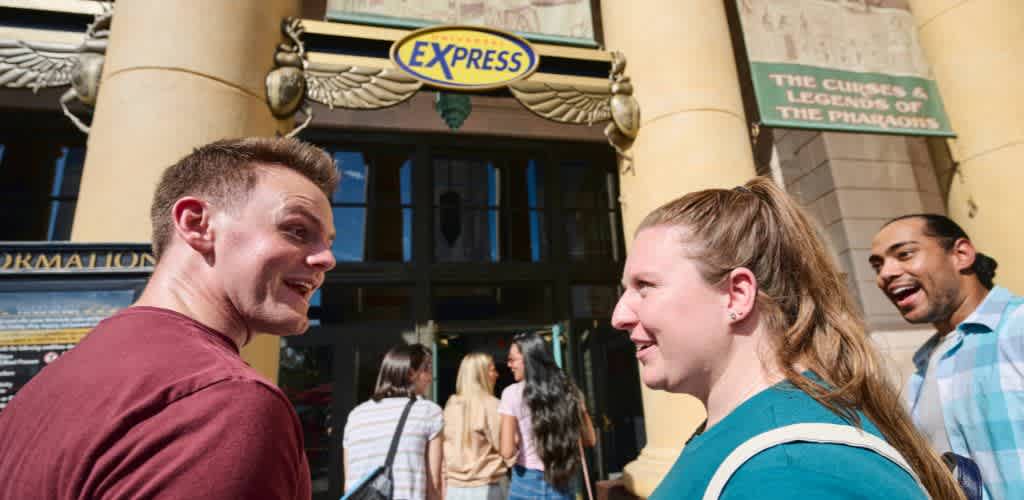 Group of happy people talking outside a building with an express sign and historical plaques, enjoying a sunny day.