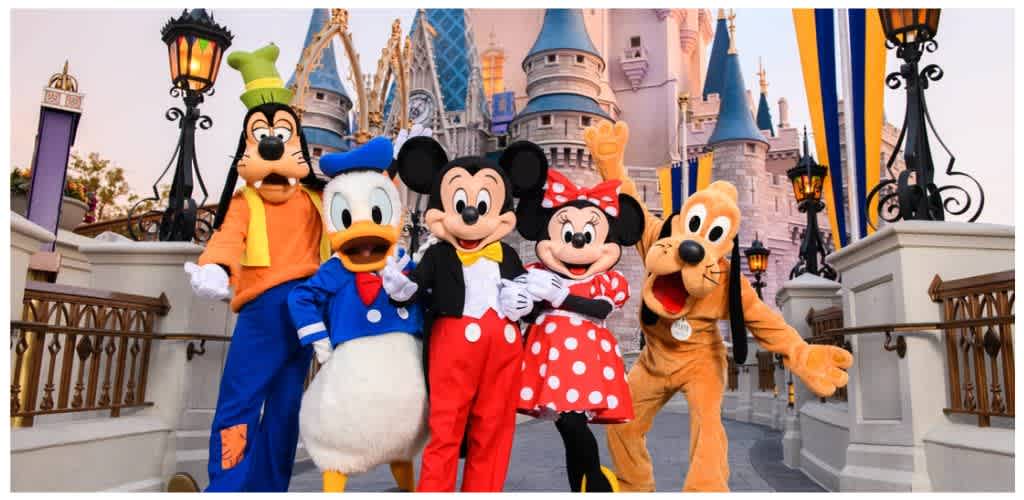 Costumed Disney characters standing on a castle bridge at Disney theme park with colorful backdrop and lantern-style lights
