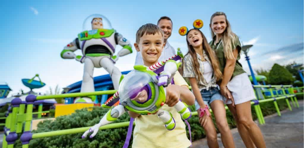 A family of four enjoys a day at an amusement park with colorful rides and characters in the background.