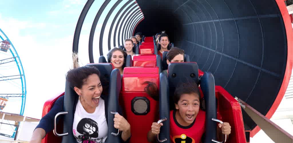 People experiencing excitement and thrill on a red roller coaster ride at an amusement park.