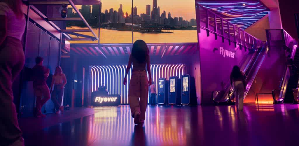 People walking through a modern indoor space with colorful lighting and city skyline views in the background
