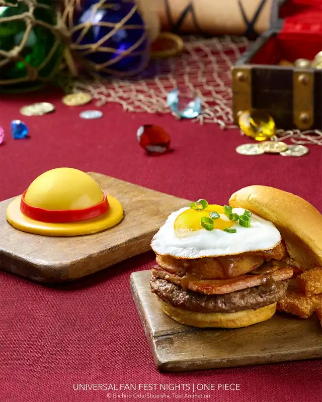 A burger with a fried egg topped with green onions, accompanied by a bun and crispy fried side on wooden boards, with colorful gemstones and decorative items in the background.