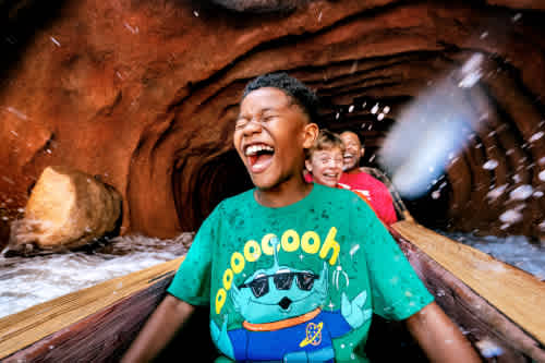 Children enjoying a thrilling water slide ride inside a tunnel with smiles and laughter on a bright day
