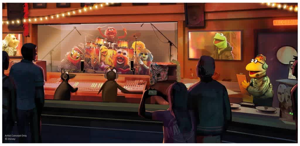 Muppets performing on stage with an audience watching and a TV screen showing Kermit the Frog in a recording studio
