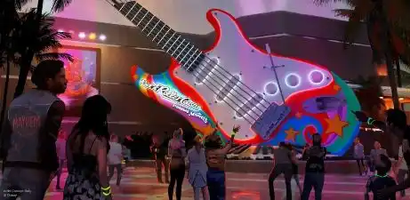 A large colorful guitar sculpture with vibrant lights located outdoors at night with people walking around and engaging with the display