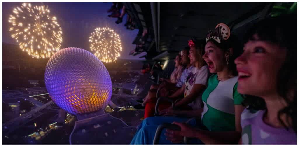 People enjoying fireworks and a spherical observation wheel at night on a carnival ride.
